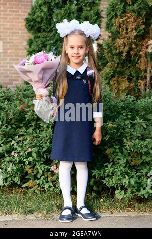 portrait of a cute little seven year old first-grader girl with a bouquet of flowers ready to go to school. back to school concept Stock Photo