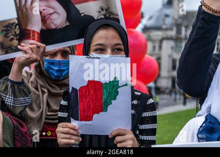 WESTMINSTER LONDON 18 August 2021.  A young female member of the British Afghan community holds a drawing with the national flag of Afghanistan in Parliament Square in reaction to the Taliban seizing power in Afghanistan. Prime Minister Boris Johnson  has recalled Parliament as MPS return  from their  summer recess to debate the crisis in Afghanistan and bring 20,000 vulnerable Afghan refugees .  Credit amer ghazzal/Alamy Live News Stock Photo