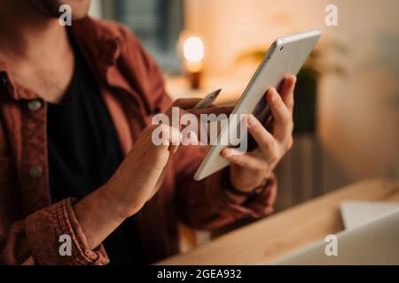 Close up caucasian male student working from home typing on digital tablet Stock Photo