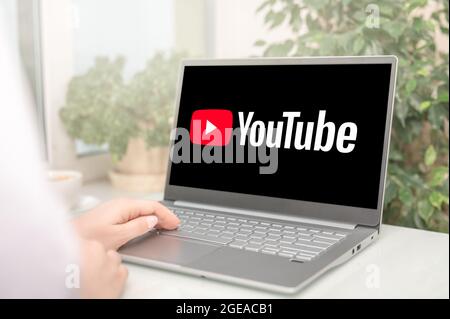Moscow, Russia - August 17, 2021 : Woman using a laptop to connect to YouTube website home page. YouTube is video sharing website. YouTube on screen l Stock Photo