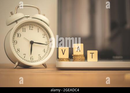 VAT and coins on desk with alarm clock and laptop. Business and managament background Stock Photo
