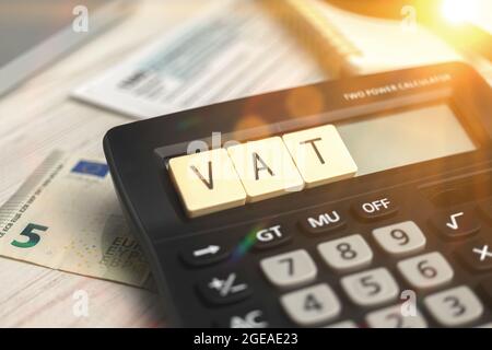 Calculating the VAT taxes. VAT word on wooden block and calculator on the business desktop Stock Photo