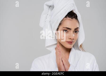 young woman with towel on head and praying hands isolated on grey Stock Photo