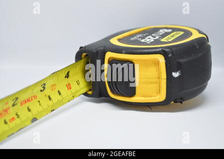 A black and yellow tape measure set against a white background Stock Photo