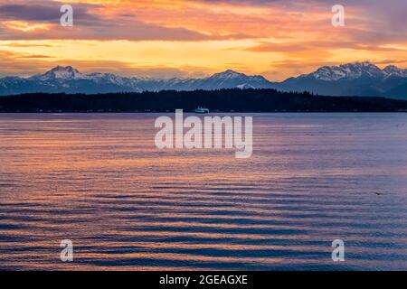 Winter sunset over Elliot Bay of Puget Sound with distant Bainbridge Island and the Olympic Mountains, viewed from Bremerton Ferry, Washington State, Stock Photo