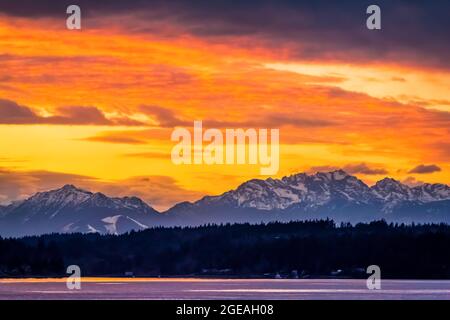 Winter sunset over Elliot Bay of Puget Sound with distant Bainbridge Island and the Olympic Mountains, viewed from Bremerton Ferry, Washington State, Stock Photo