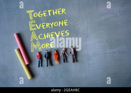 TEAM acronym - Together Everyone Achieves More chalk handwriting and miniature people Stock Photo