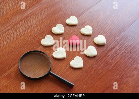 Magnifying glass, red heart and white heart. Finding true love valentine concept. Stock Photo