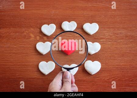 Magnifying glass, red heart and white heart. Finding true love valentine concept. Stock Photo