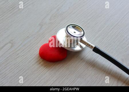 Red heart and stethoscope on white wooden background. Healthcare and medical concept Stock Photo