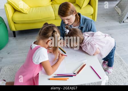 Cute happy children with teacher drawing together in classroom Stock ...