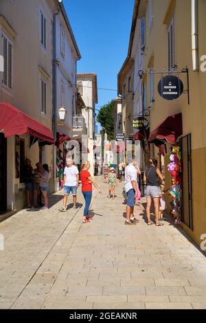 Tourists in an old town alley with stores in Krk in Croatia Stock Photo