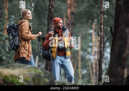 man holding map near cheerful woman with hiking sticks Stock Photo