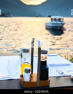 A beautiful romantic tourist destination by the edge of Kotor Bay in late summer with cutlery,condiments and napkins freshly arranged for the evening Stock Photo