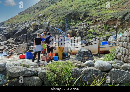 A fisherman talking to tourists about his catch of fish he has just landed at Penberth Cove, Cornwall, England, UK Stock Photo