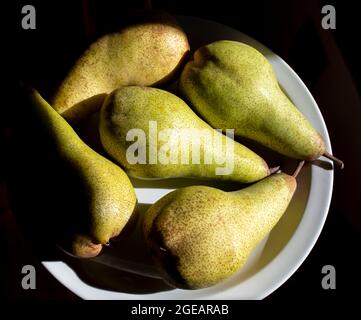 Pears rippening on a plate in the sun. Stock Photo