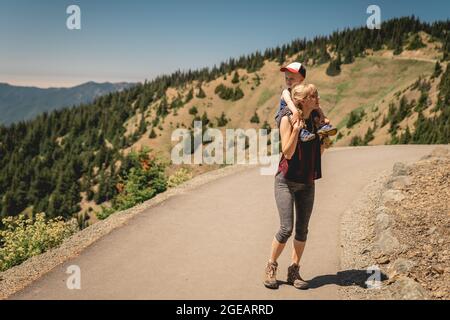 Mother carrying young son on shoulders as they hike Hurricane Hill in Olympic National Park. Stock Photo