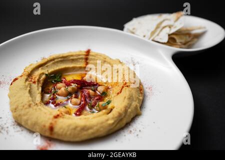 hummus with chickpea, olive oil, paprika and pita bread on black background Stock Photo