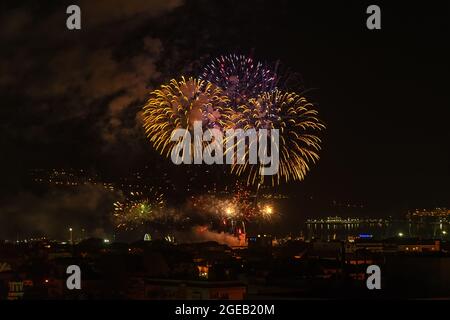 Bright fireworks in the night sky over seashore city and sea. Varna celebrates the city day with colorful fireworks at midnight. Night outdoors scene. Stock Photo