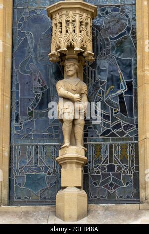 One of the stone sculptures against a stained glass window on the front facade of Bath Abbey. Stock Photo