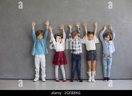 Studio group portrait of happy little children standing together and raising hands Stock Photo