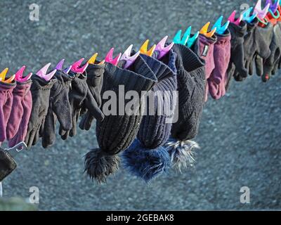 Bright sunshine on washing line with hats and gloves and colourful clothes-pegs on a farm in the Eden Valley Cumbria, England,UK Stock Photo