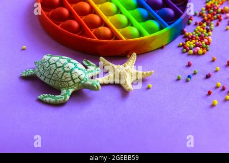 Trendy silicone anti-stress toy Pop it in rainbow colors on a violet background. Stock Photo