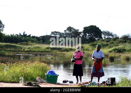 Two women are seen washing dishes at a river in Mchinji. Many people use open water sources. Mchinji, Malawi. Stock Photo