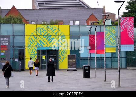 People walk outside the entrance of the National Football Museum in Manchester City centre, England, UK. Stock Photo
