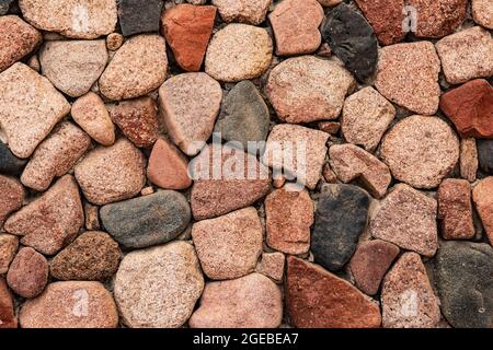 Beautiful Background from natural stones of different colors. Decorative masonry of the wall from large textured stones of various colors. Rustic wall Stock Photo