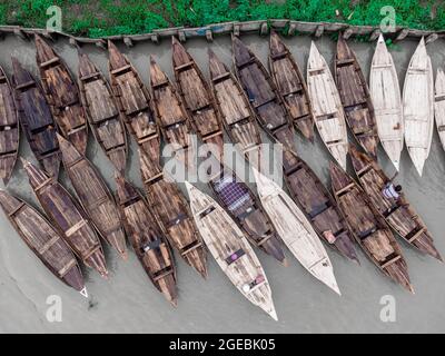 Barishal, Bangladesh, August 18, 2021: Aerial view of the Boat makers manufacture wood Boats  at   “Noukar Haat” (boat market) in Kuriana under the Swarupkathi upazila of Pirojpur district.  The Marketplace of Noukar Haat with a length of  two-kilometre-long  is noted for the trade in different varieties of boats during the monsoon season. The market runs every Friday from May to November. “Panis” or “Pinis”, “Dingi” and “Naak Golui” are the types of boats available for sale, built by local craftsmen from the Muktahar, Chami, Boldia, Inderhaat, Boitha Kata, Dubi and Kathali villages. Credit: M Stock Photo