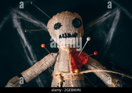 Voodoo rag doll with buttons instead of eyes and studded with needles, close-up top view. Stock Photo