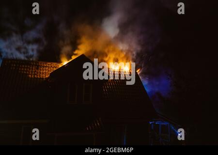 Wooden rural house is burning in fire at night. Stock Photo