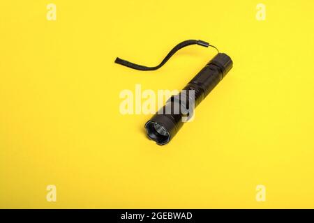 black flashlight shocker on a yellow background. Stock Photo