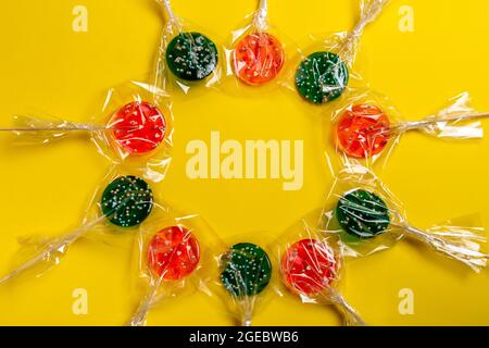 multi-colored lollipops on a stick on a yellow background. Stock Photo