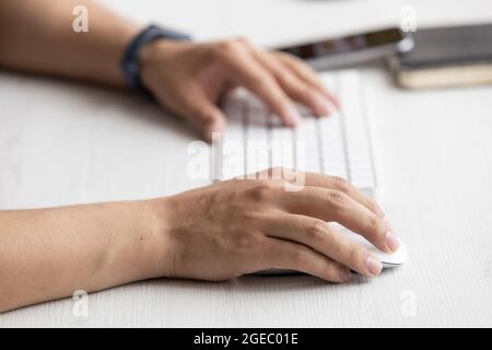 person typing on a modern keyboard, technology and modernity at work desk, in the background a cell phone, notebook, office objects Stock Photo