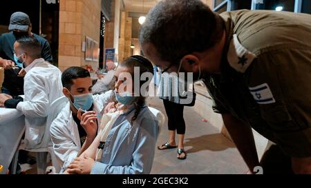 A religious Jewish boy receives a dose of the Pfizer-BioNtech COVID-19 vaccine against the coronavirus disease at the open night vaccination center in the city hall complex on August 17, 2021 in Jerusalem, Israel. Israel urged more young people to be vaccinated, citing new outbreaks attributed to the more infectious Delta variant. Stock Photo