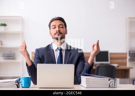Young businessman employee doing yoga exercises during break Stock Photo