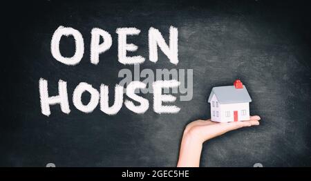 Open house real estate sale sign on black chalkboard texture with realtor hand showing home. House hunting Stock Photo