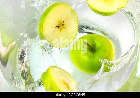 Close up green apples falling in water with splash. Stock Photo