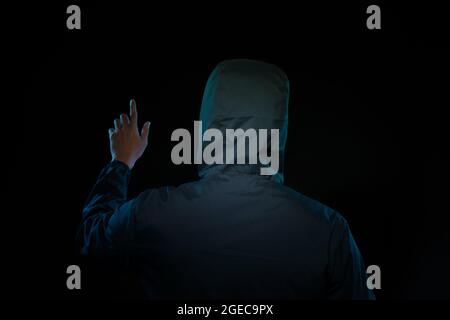 Man wearing hood in dark room Stock Photo