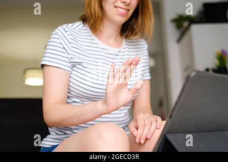 Smiling young woman using laptop for online talking with colleges or friends. Freelancer working at home. Stock Photo