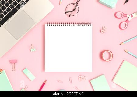 Blank notepad mockup. Top view of laptop and stationery on a pink pastel background. Workspace concept. Stock Photo