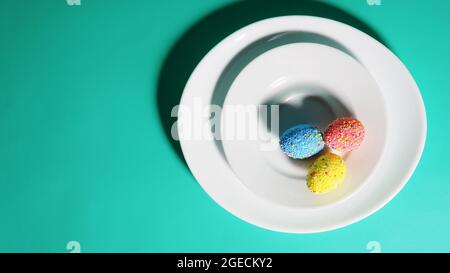Colorful eggs on a plate, bright green blue background, Easter concept. Stock Photo