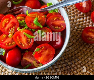 A bowl of fresh cherry tomatoes with olive oil and chives Stock Photo