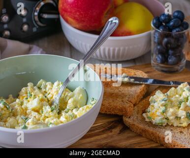 High protein and low fat egg salad made with boiled eggs, cottage cheese and chives served in a bowl with toasted whole wheat bread on rustic table Stock Photo