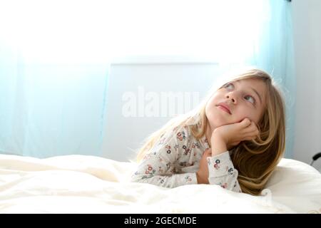 Young girl of seven daydreams in her bedroom Stock Photo
