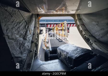 Loading of luggage to airplane. Suitcases on conveyor belt to plane. Stock Photo