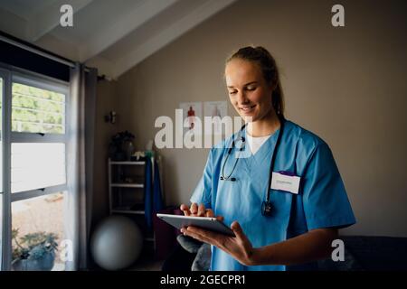 Caucasian female nurse preparing for online consultation with patient over video call standing in clinic Stock Photo