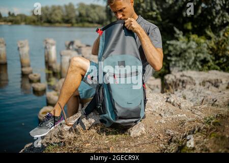 Young man packing his travel backpack with a camera gear. Stock Photo